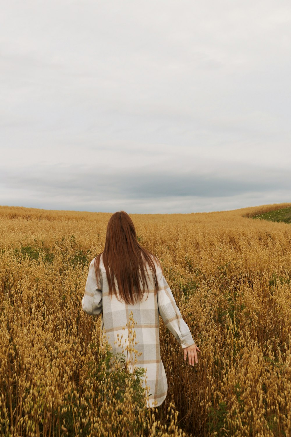 a woman walking through a field of tall grass