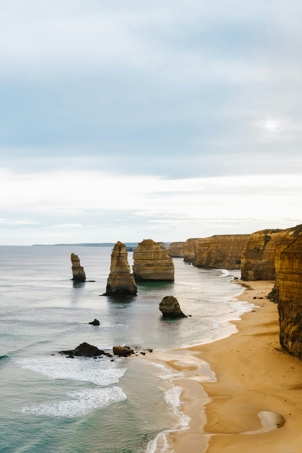 a view of a beach with a rock formation in the water