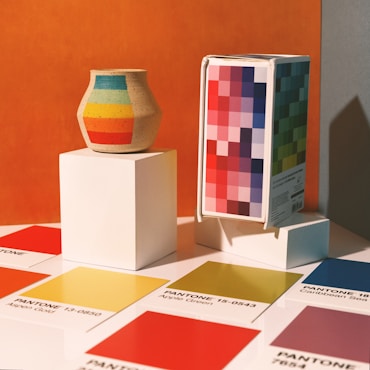 a colorful vase sitting on top of a white pedestal