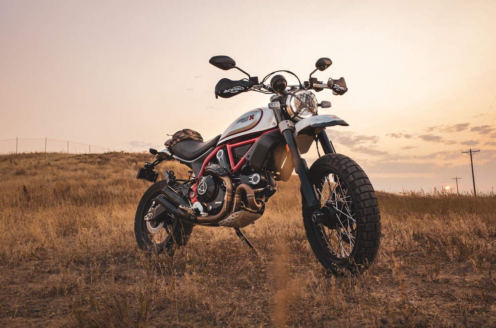 a motorcycle parked in a field at sunset