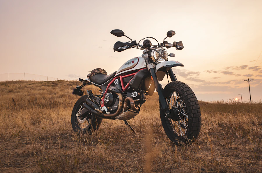 Ducati Scrambler motorcycle parked in a field at sunset