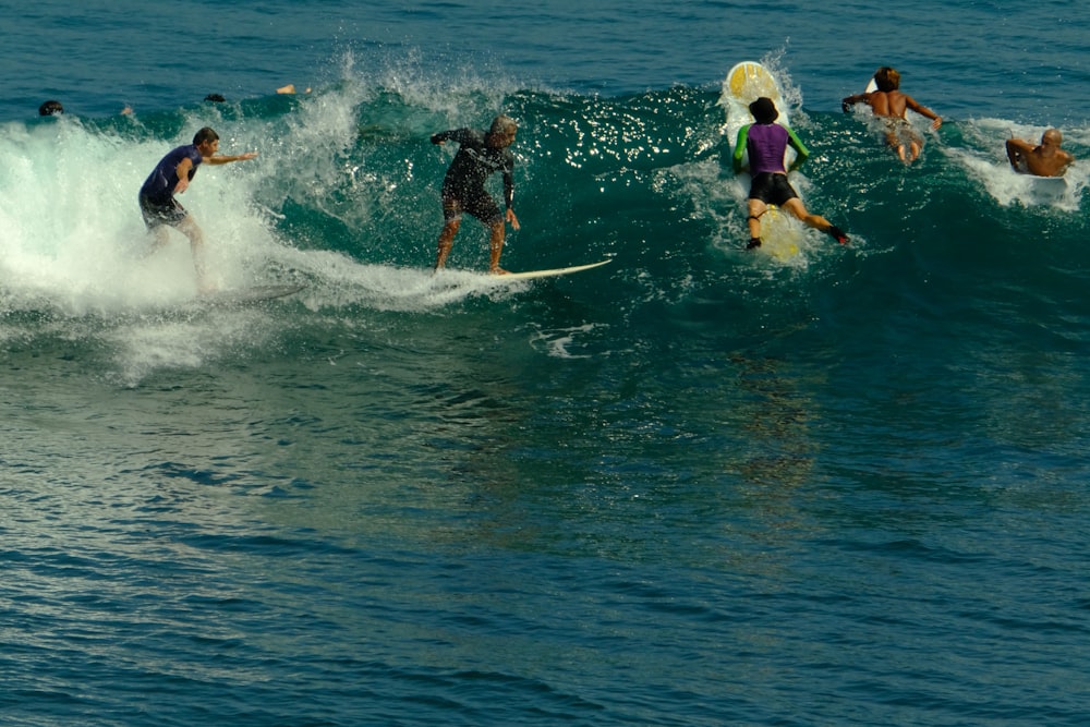 a group of people riding surfboards on top of a wave