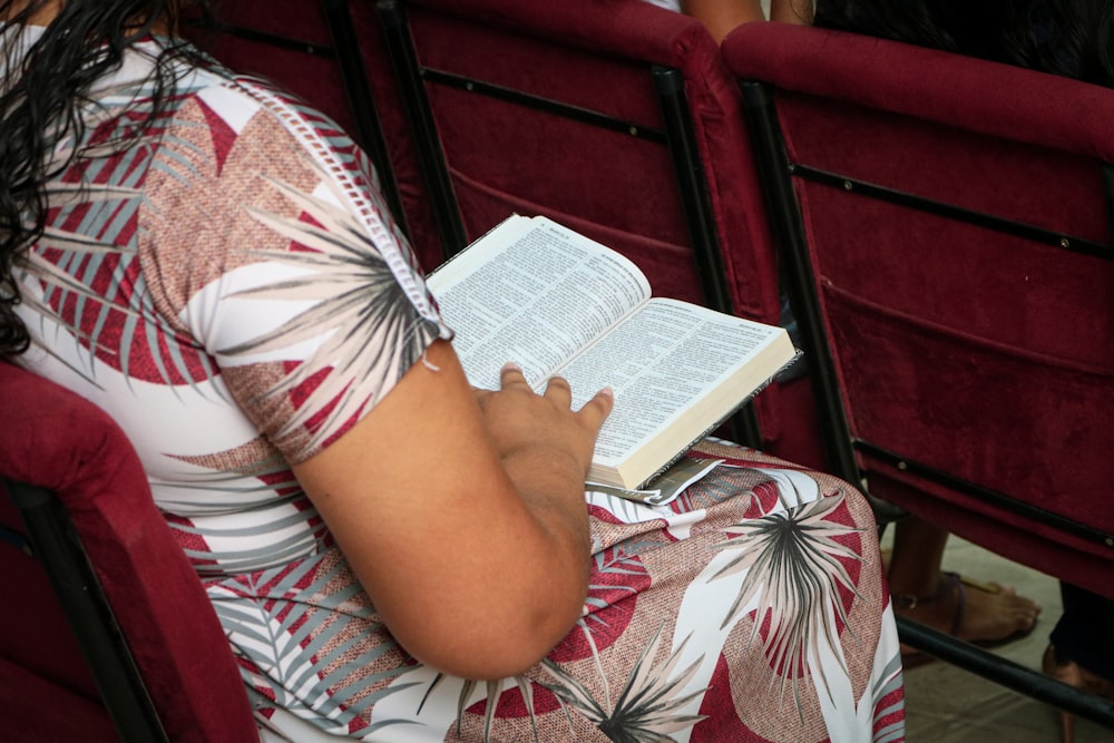 uma mulher sentada em uma cadeira lendo um livro