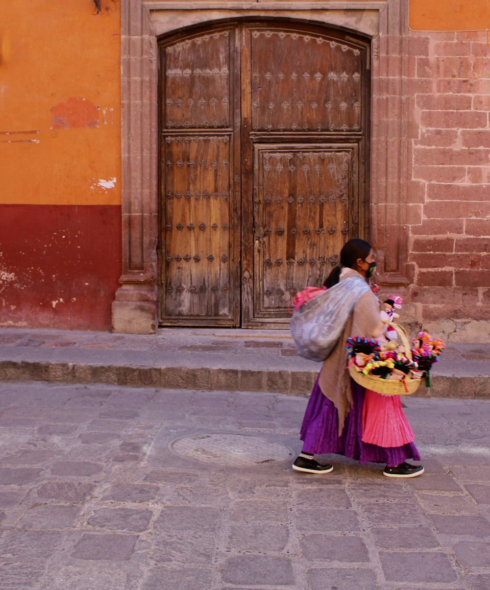 a woman walking down a street carrying a basket of flowers