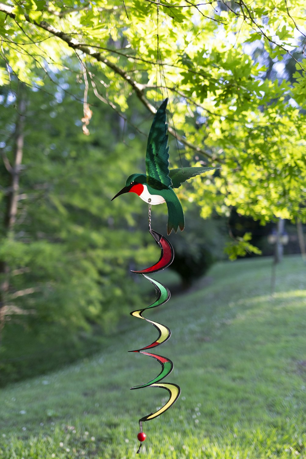 a colorful bird wind chime hanging from a tree