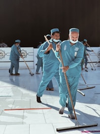 a group of men in blue uniforms with brooms
