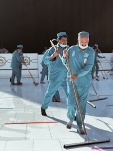 a group of men in blue uniforms with brooms