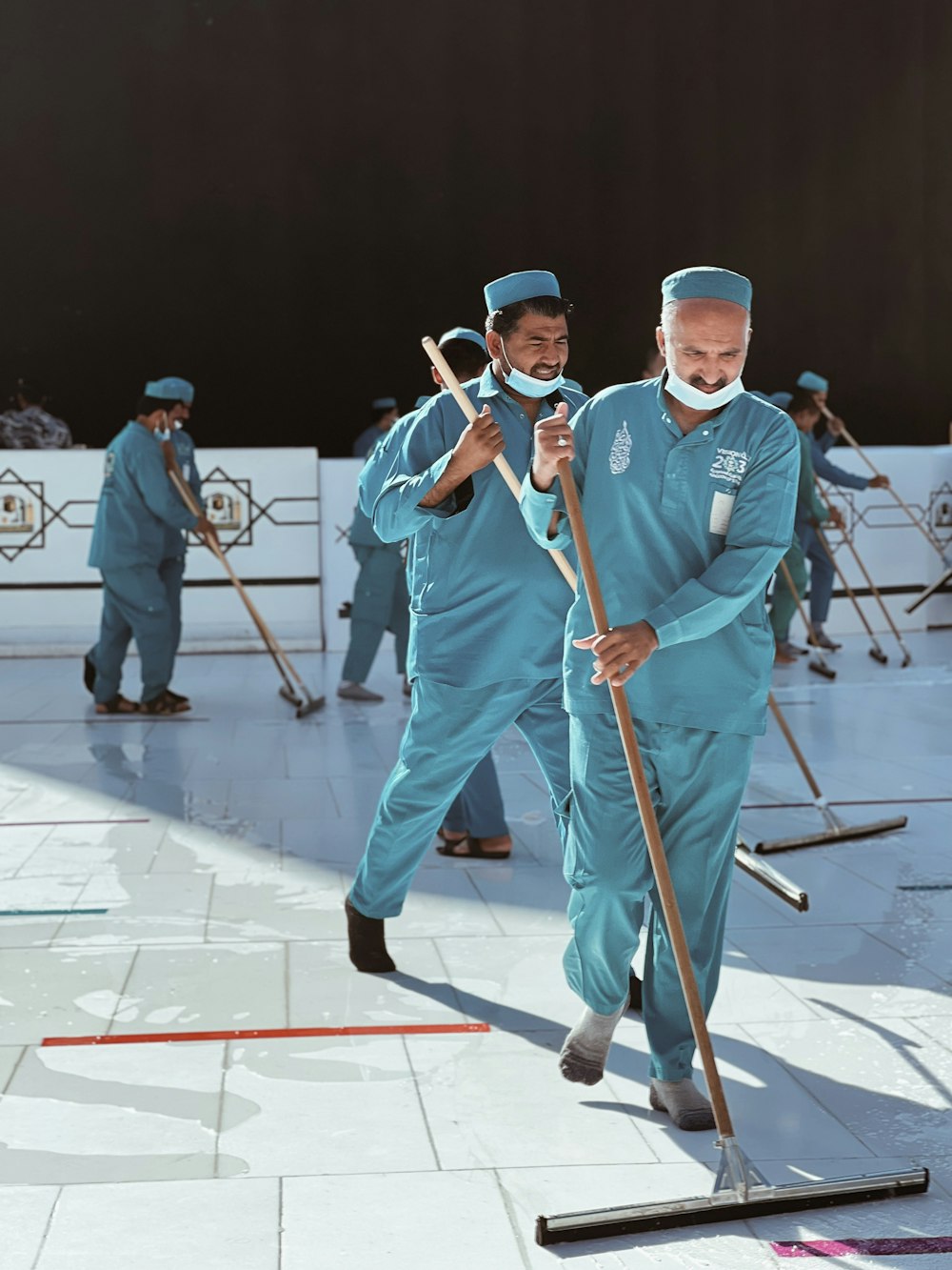 a group of men in blue uniforms with brooms