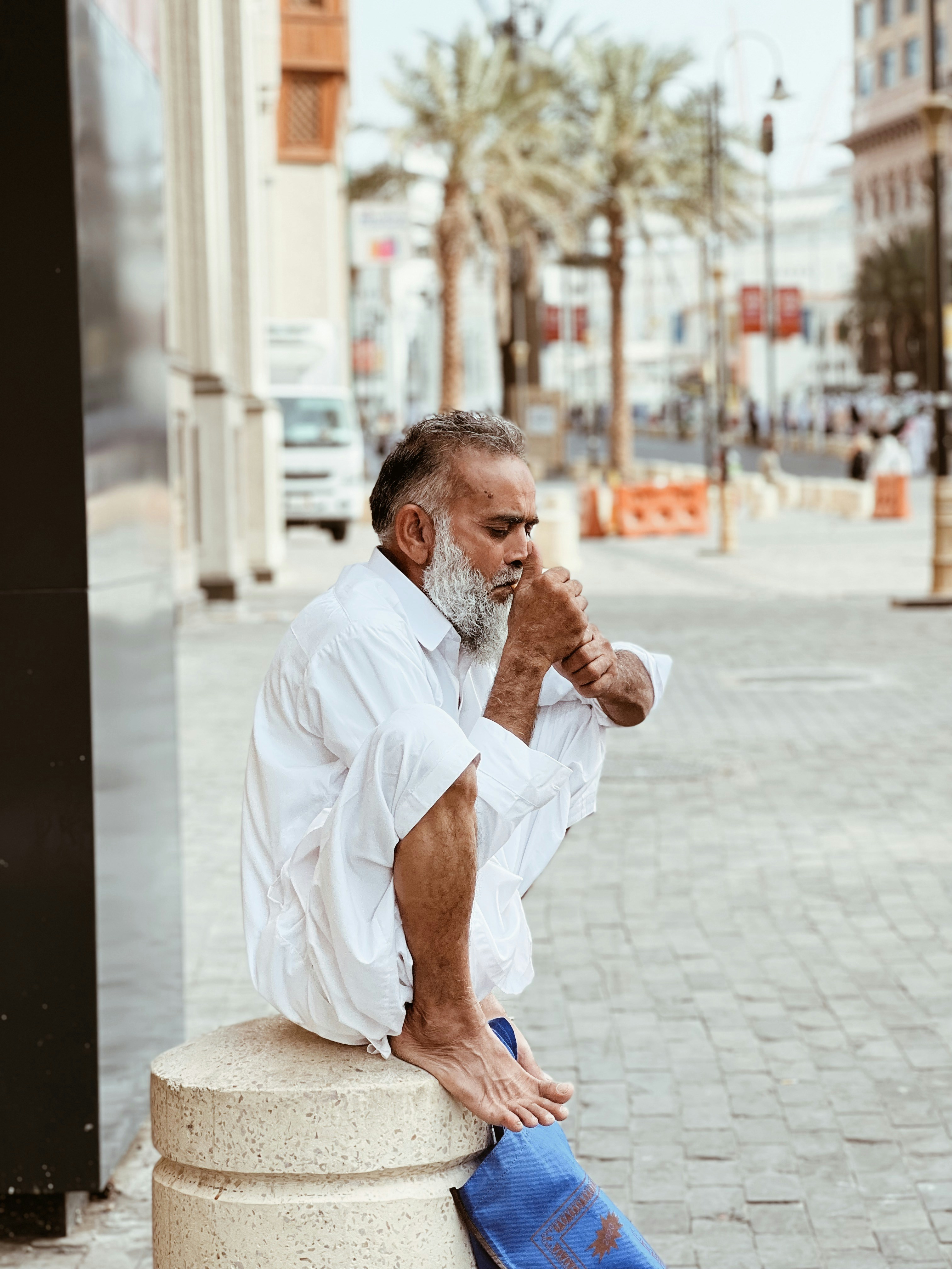 a man with a white beard sitting on a pillar