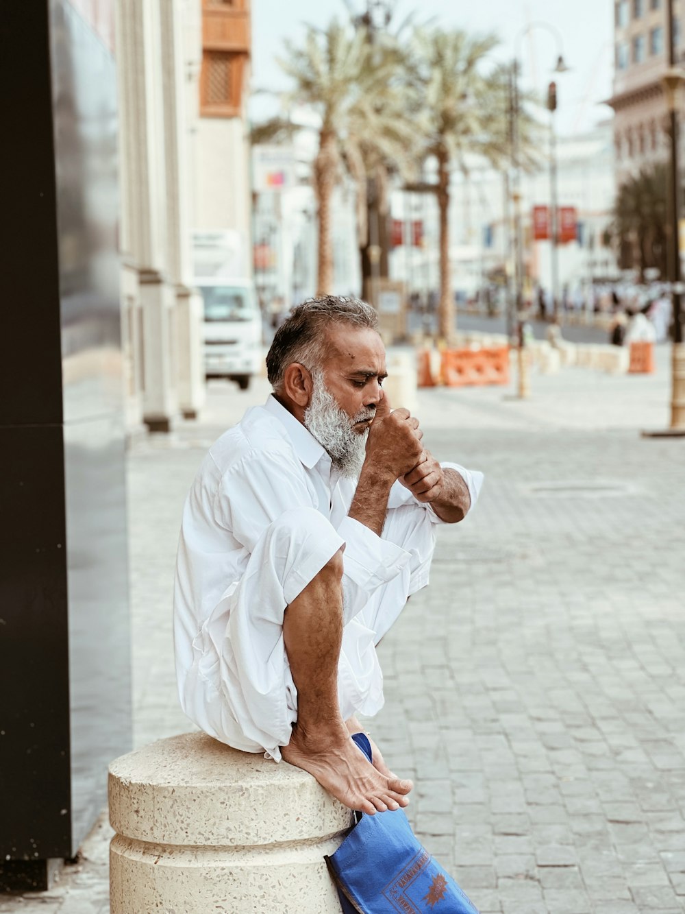 a man with a white beard sitting on a pillar