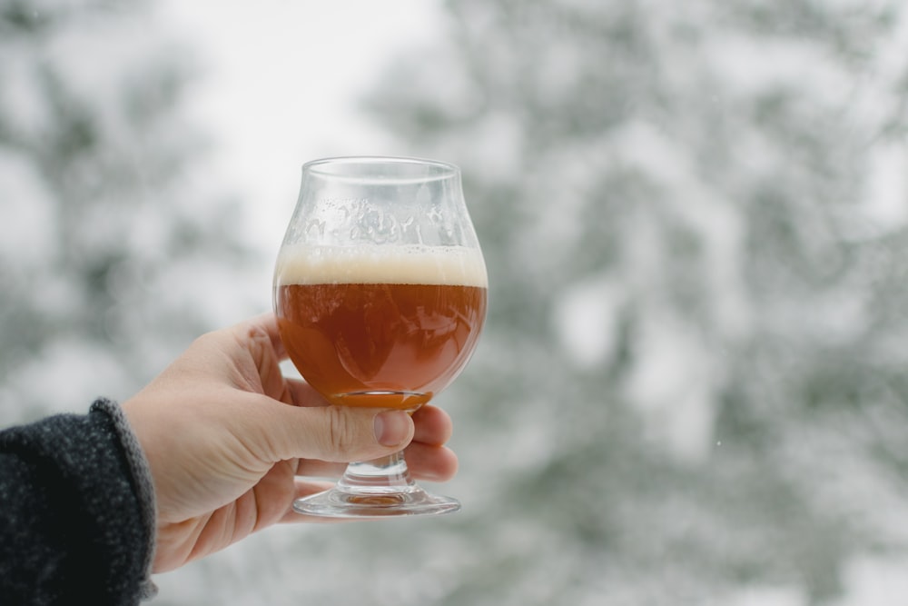 a person holding a glass of beer in their hand