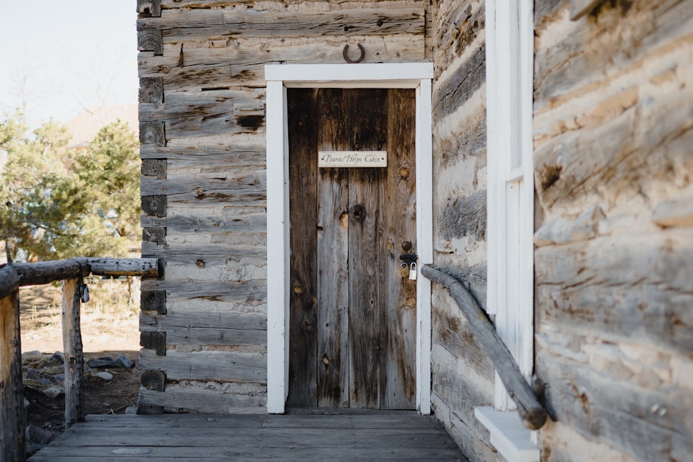 a wooden house with a door and a sign on it