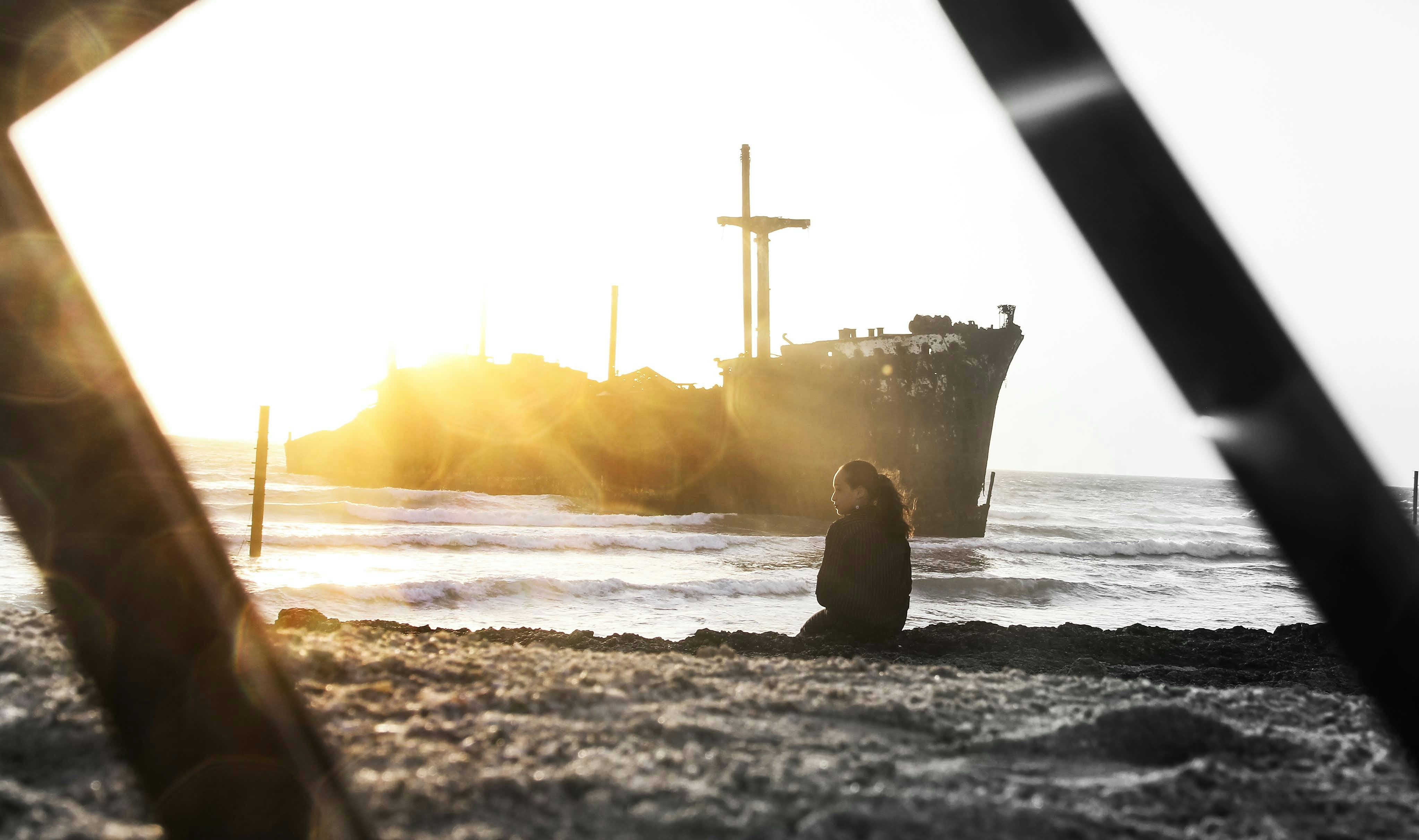 a person sitting on a beach next to a boat
