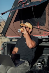 a man sitting in the back of a truck drinking from a can