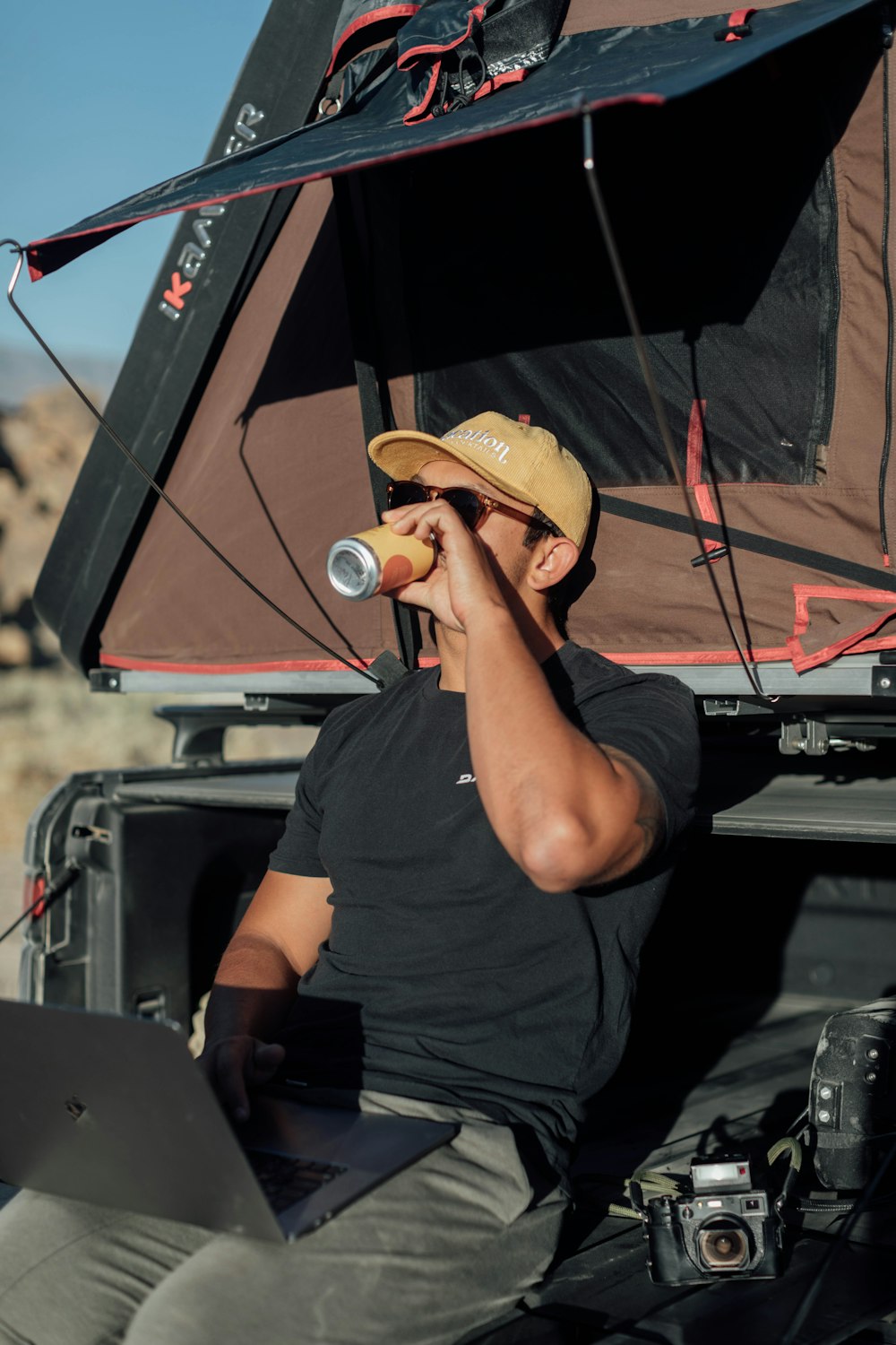 a man sitting in the back of a truck drinking from a can