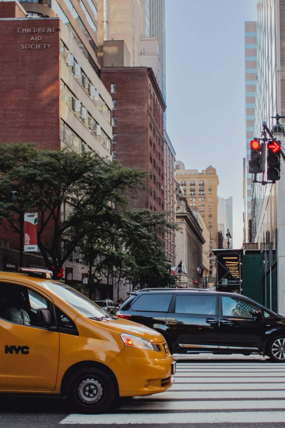 a yellow taxi cab driving down a street next to tall buildings