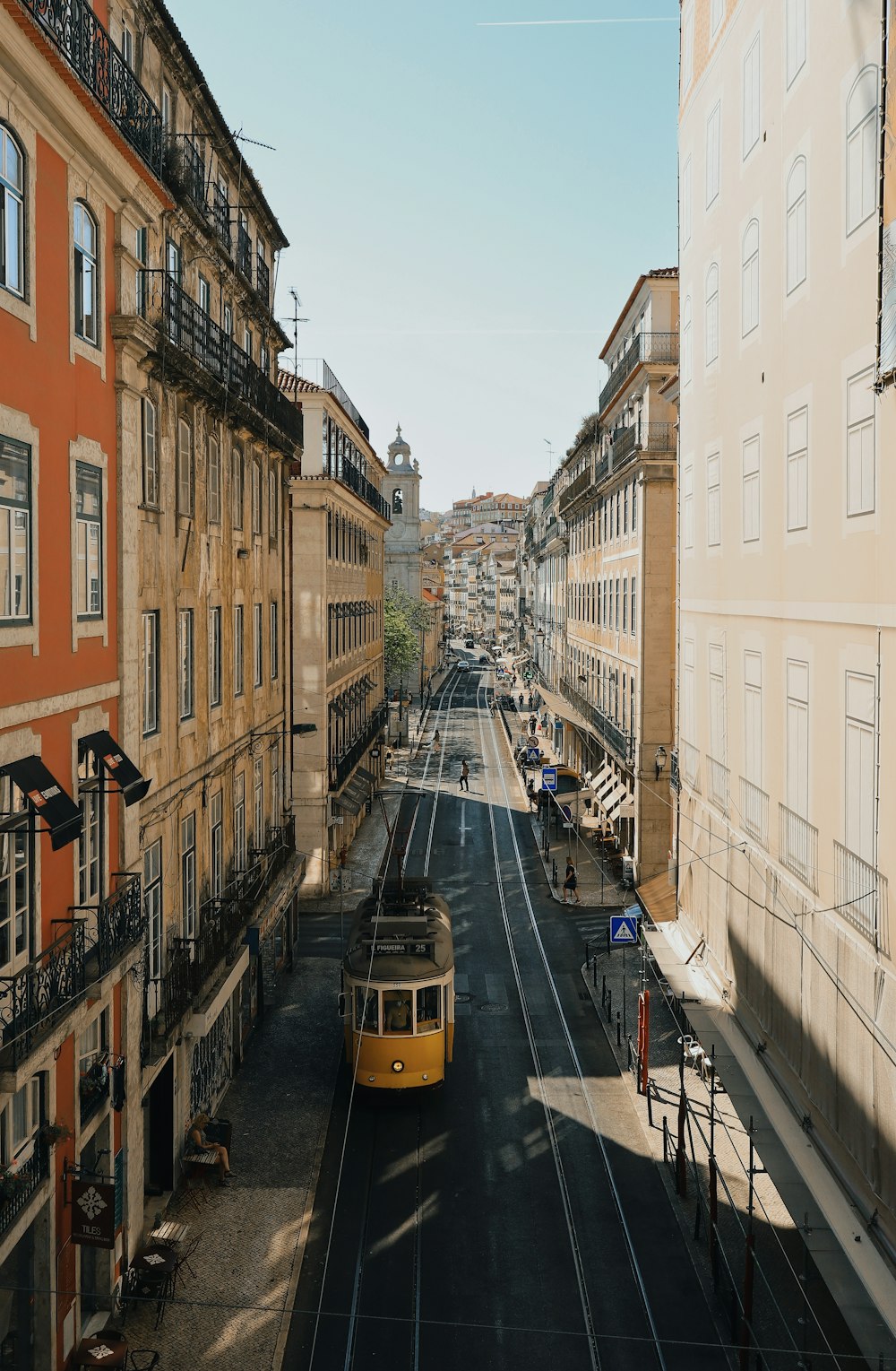 a yellow trolley is going down a city street