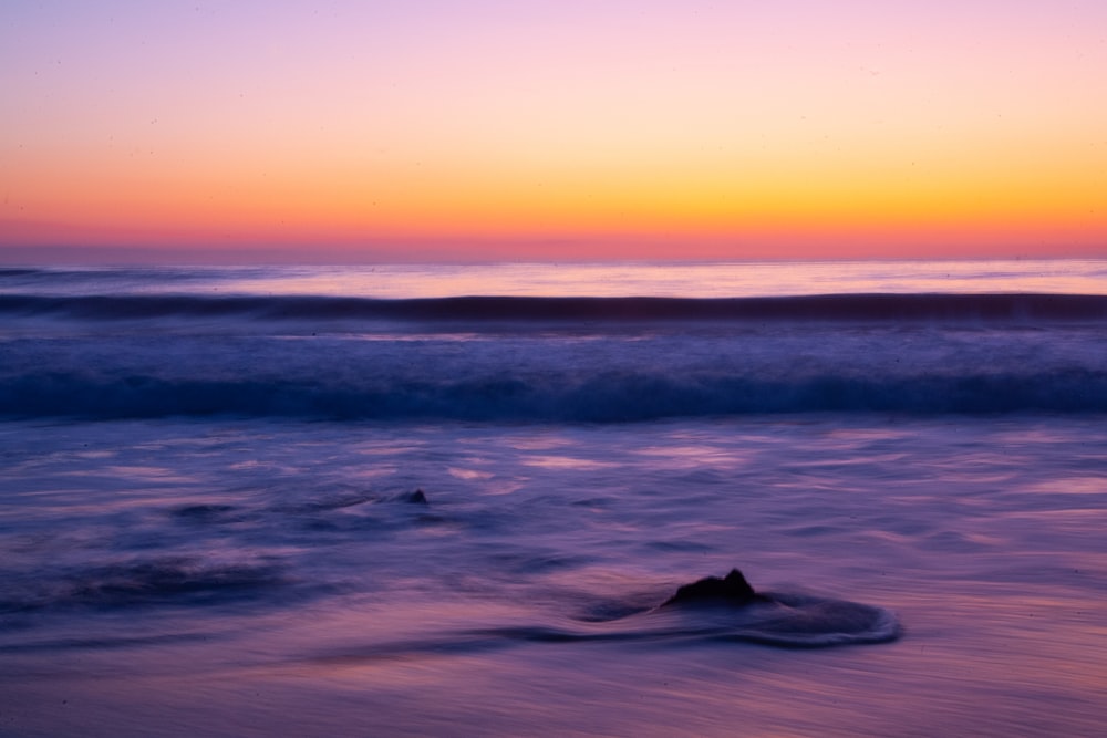 a wave rolls in on the beach at sunset