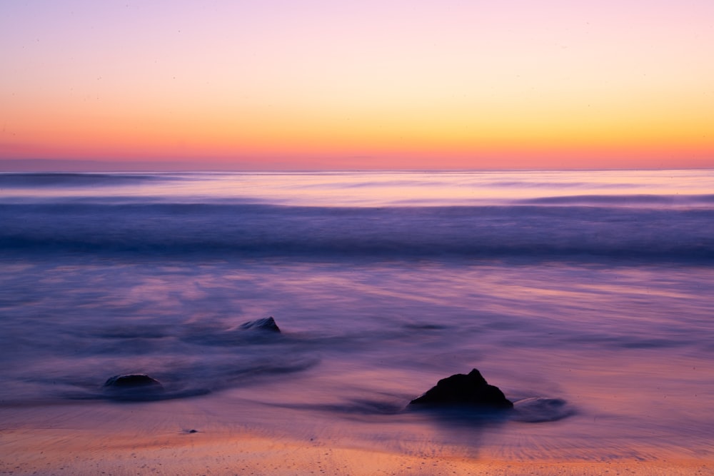 Ein Sonnenuntergang über dem Ozean mit einem Felsen im Vordergrund