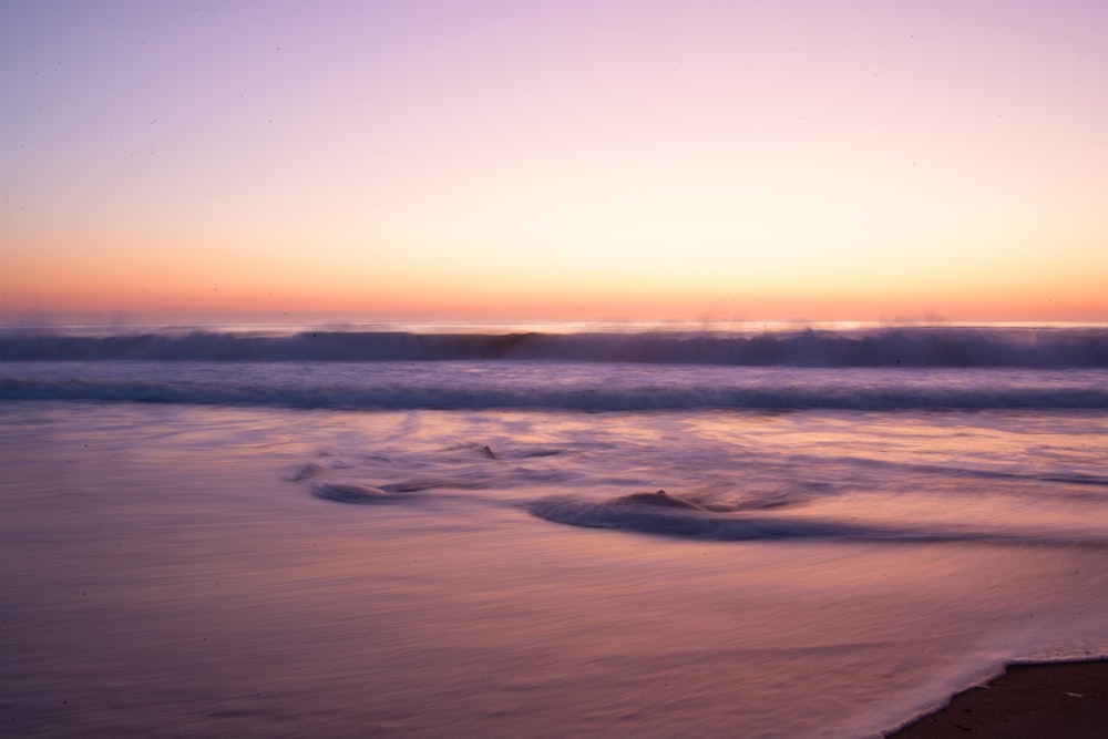 the sun is setting over the ocean waves