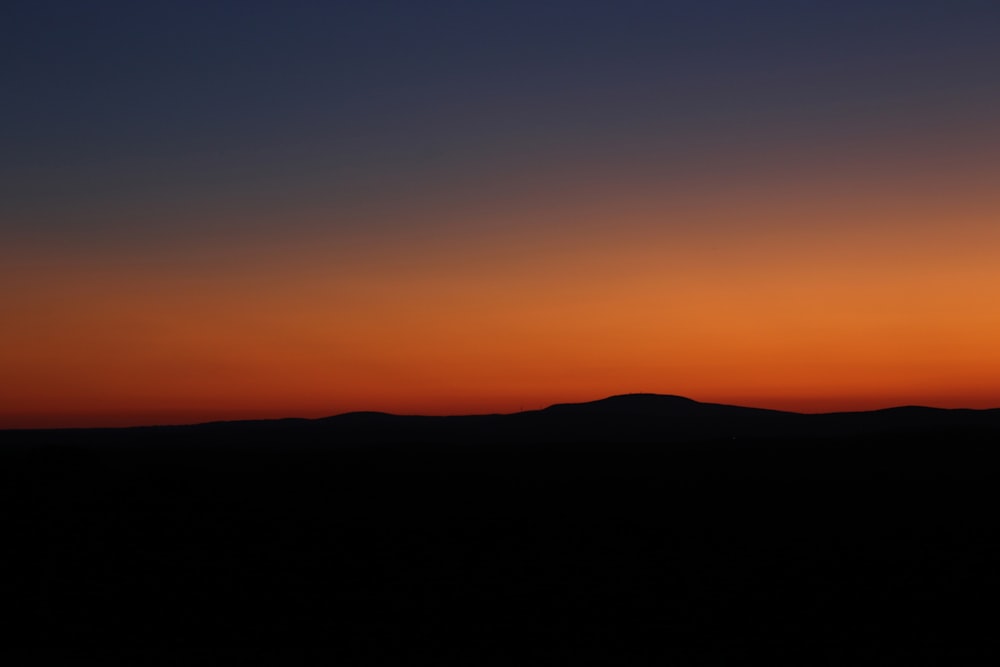 the sun is setting over a mountain range