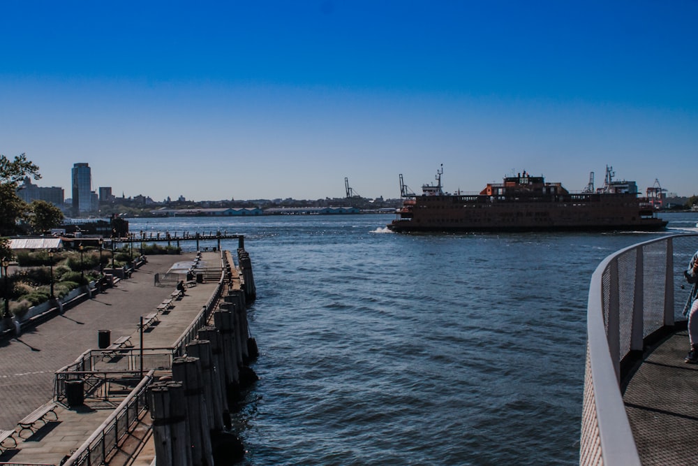 a large boat traveling down a river next to a pier