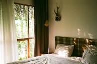 A cozy bedroom with natural light streaming through large windows.