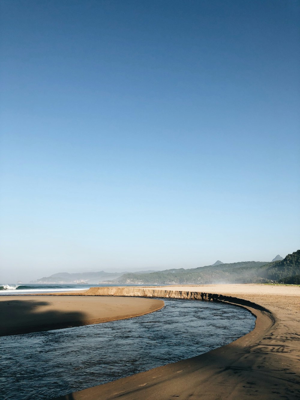 a body of water sitting next to a sandy beach