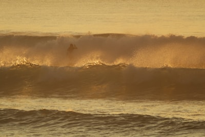 A happy rider enjoying sunset waves on a glowing electric surfboard.