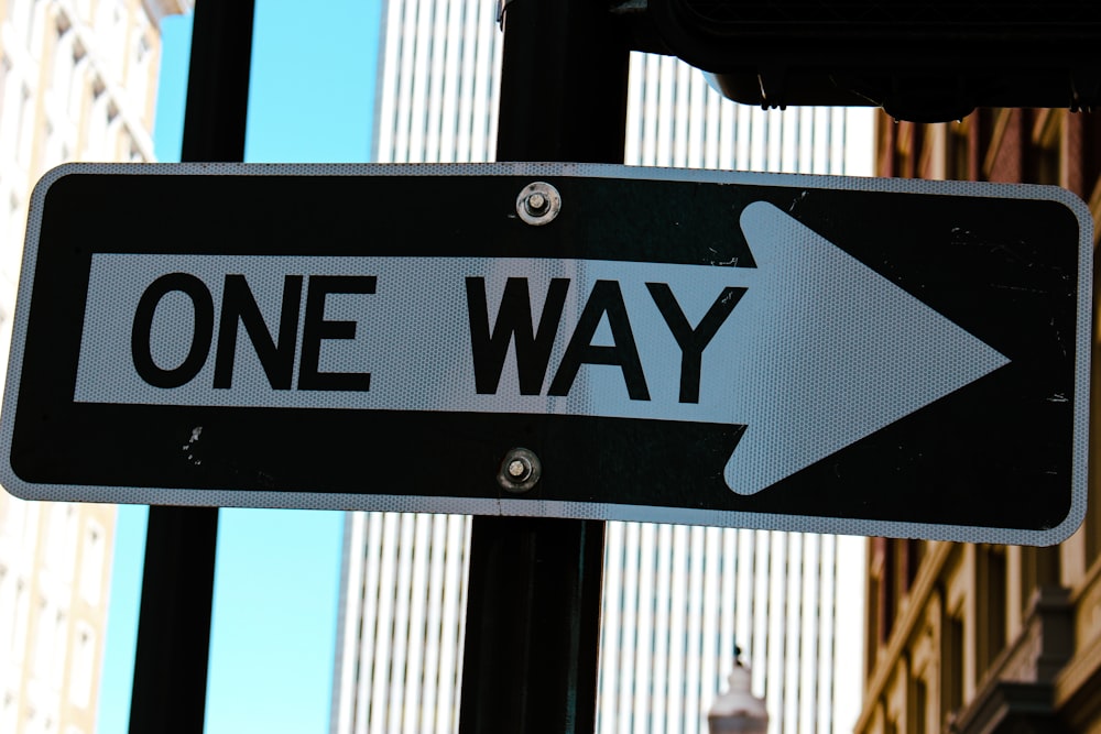 a one way sign with a building in the background