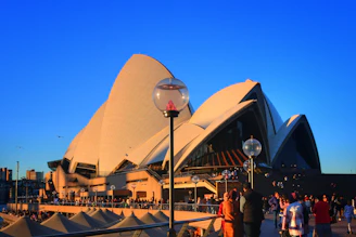 The Sydney Opera House with its white sails glowing under a bright sunny sky in Australia.