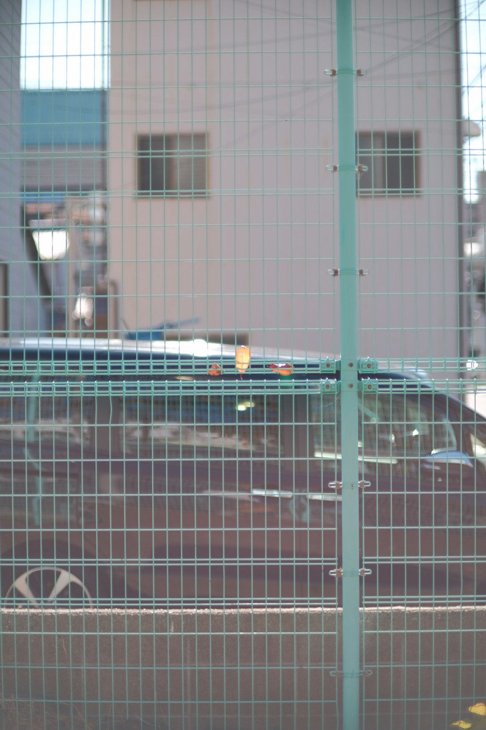 a car behind a fence with a building in the background