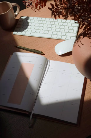 An inviting, cozy workspace with a laptop, a cup of tea, and an open productivity planner on a wooden desk.