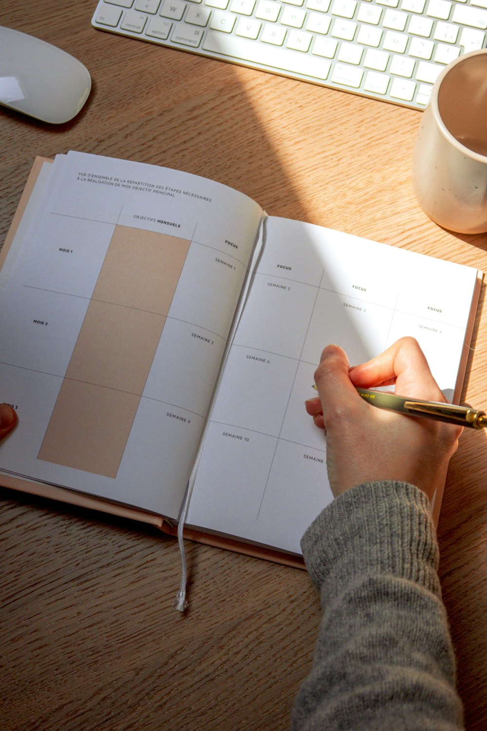 a person holding a pen and writing on a book