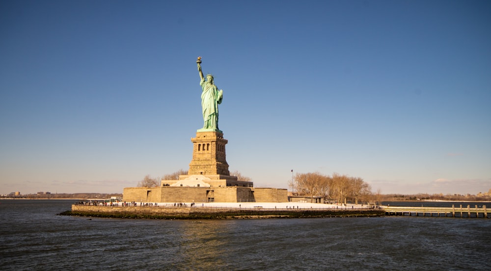 the statue of liberty stands in the middle of the water