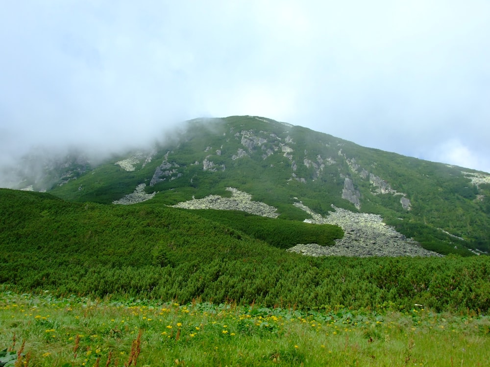 una grande montagna verde coperta di nuvole ed erba