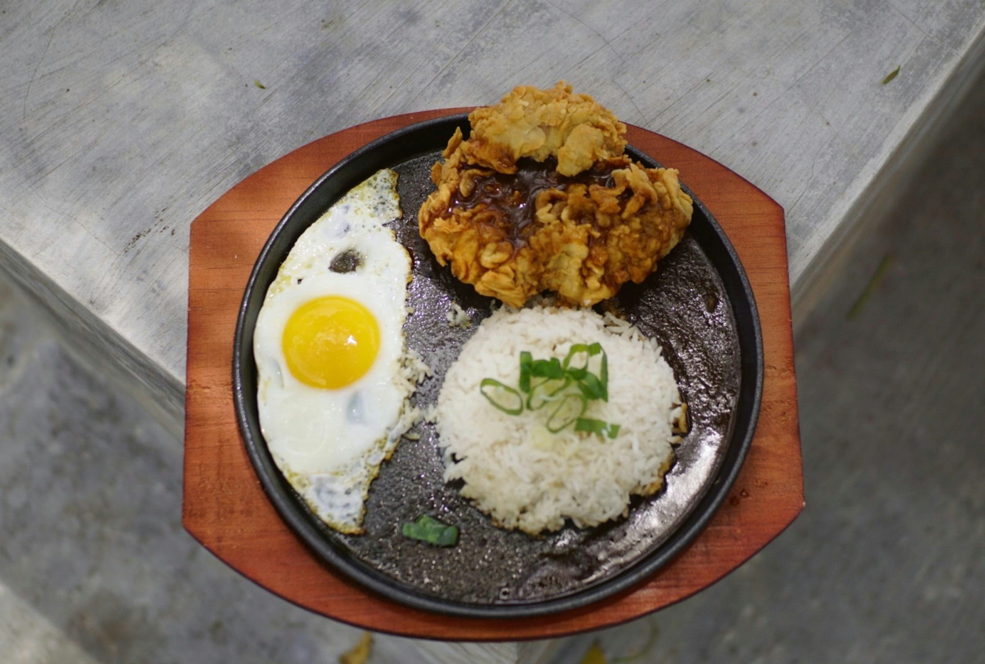 Fried chicken, rice and egg on a sizzling plate