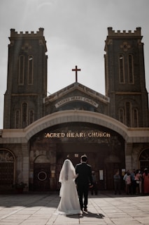 Bride and groom exchanging garlands under a floral arch at CSI Holy Trinity Church