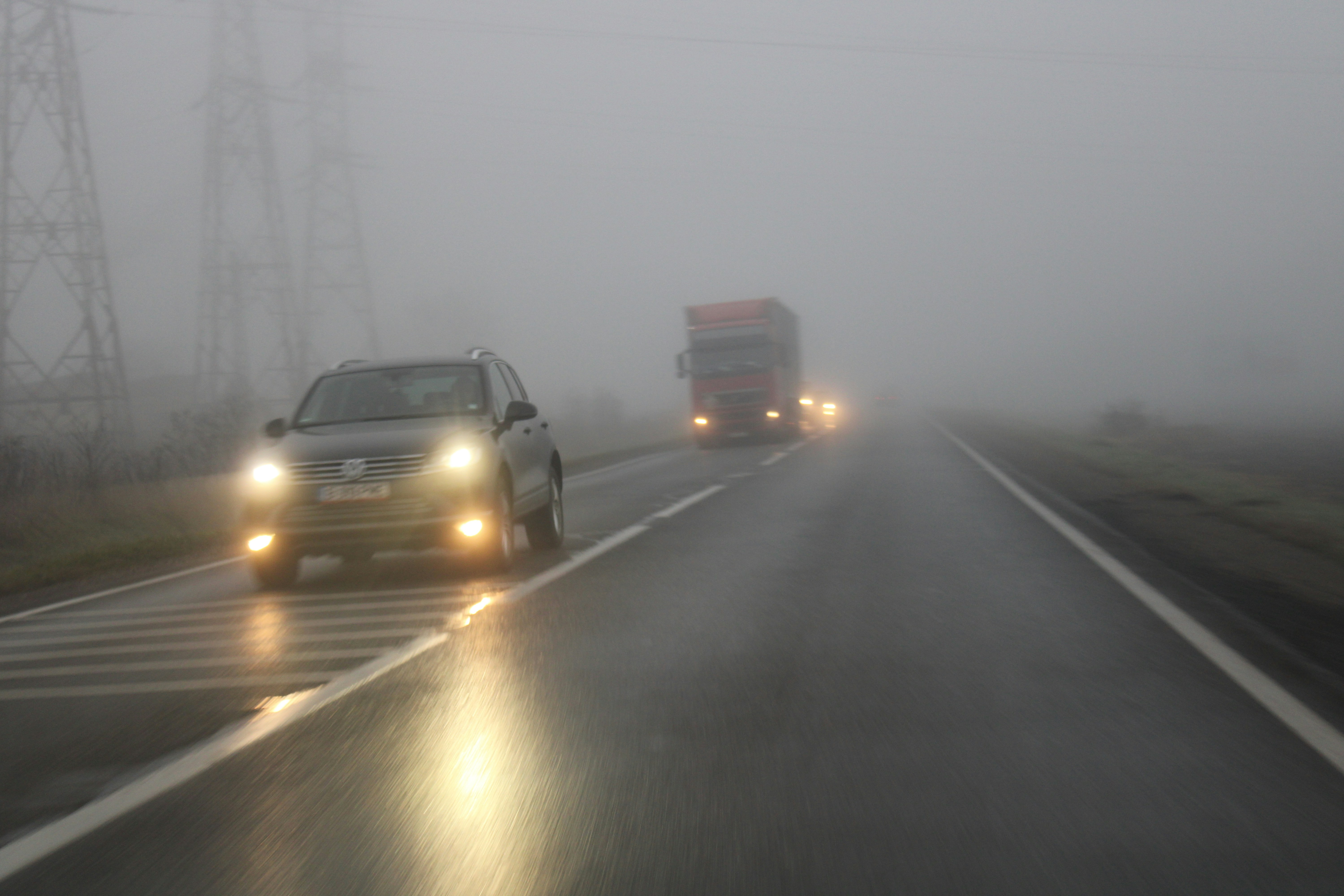 a couple of cars driving down a foggy road