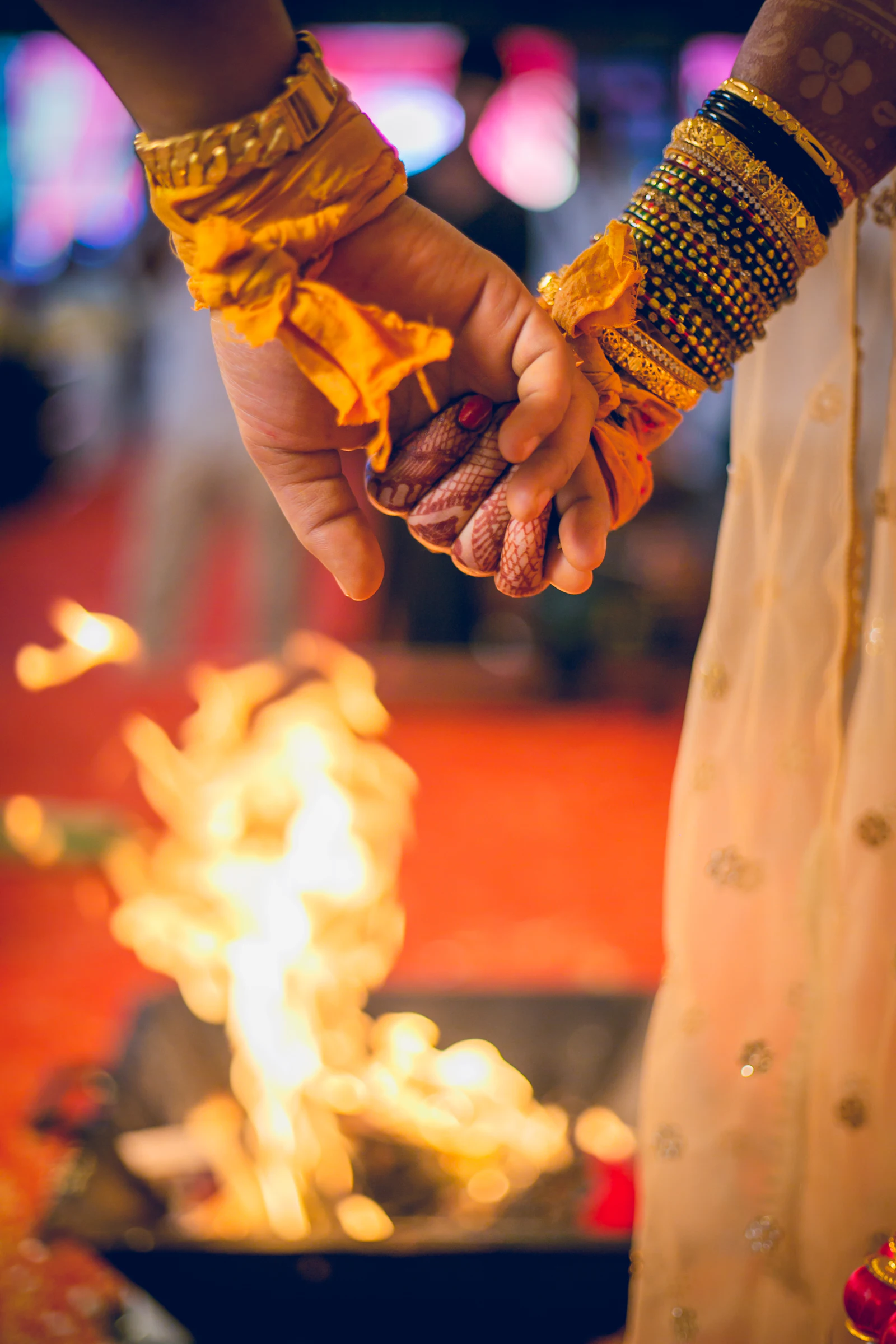 A bride and groom’s hands joined beside the sacred fire during a Hindu wedding ritual