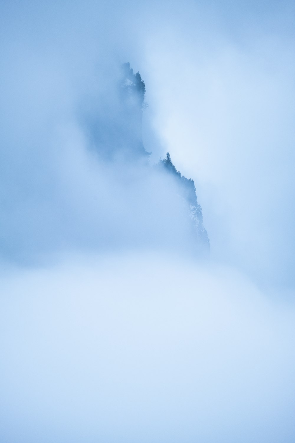 a very tall mountain in the middle of a foggy sky