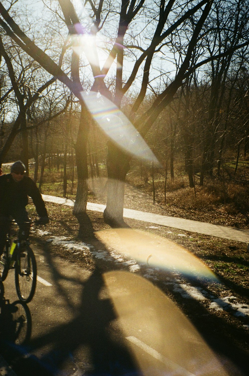 a man riding a bike down a street next to a park