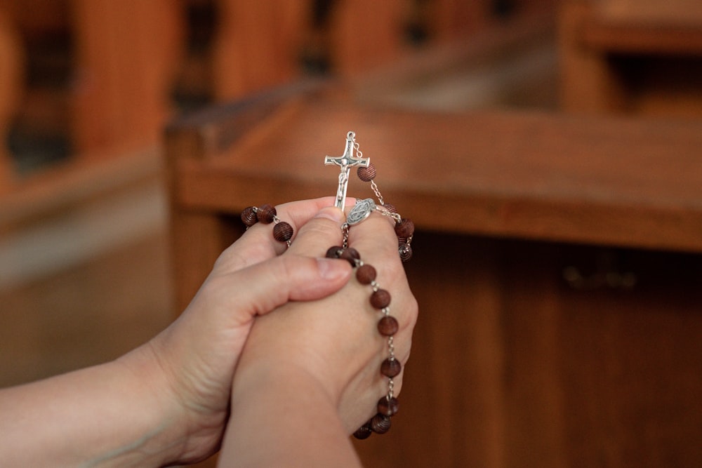 a person holding a rosary with a cross on it