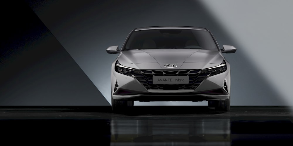 the front end of a silver car in a dark room