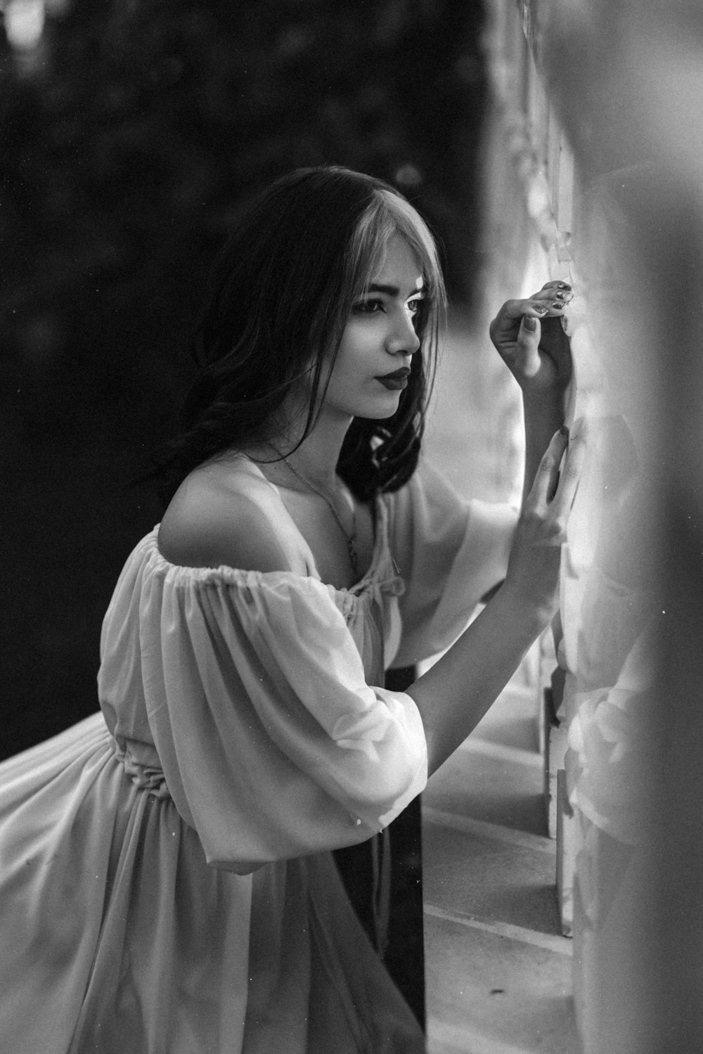 a black and white photo of a woman leaning against a wall