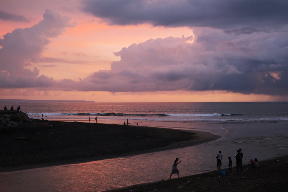 a group of people standing on top of a beach next to the ocean