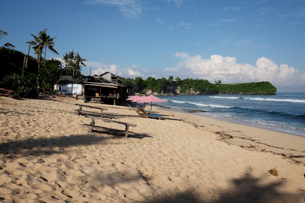 a sandy beach with a hut and a pink umbrella