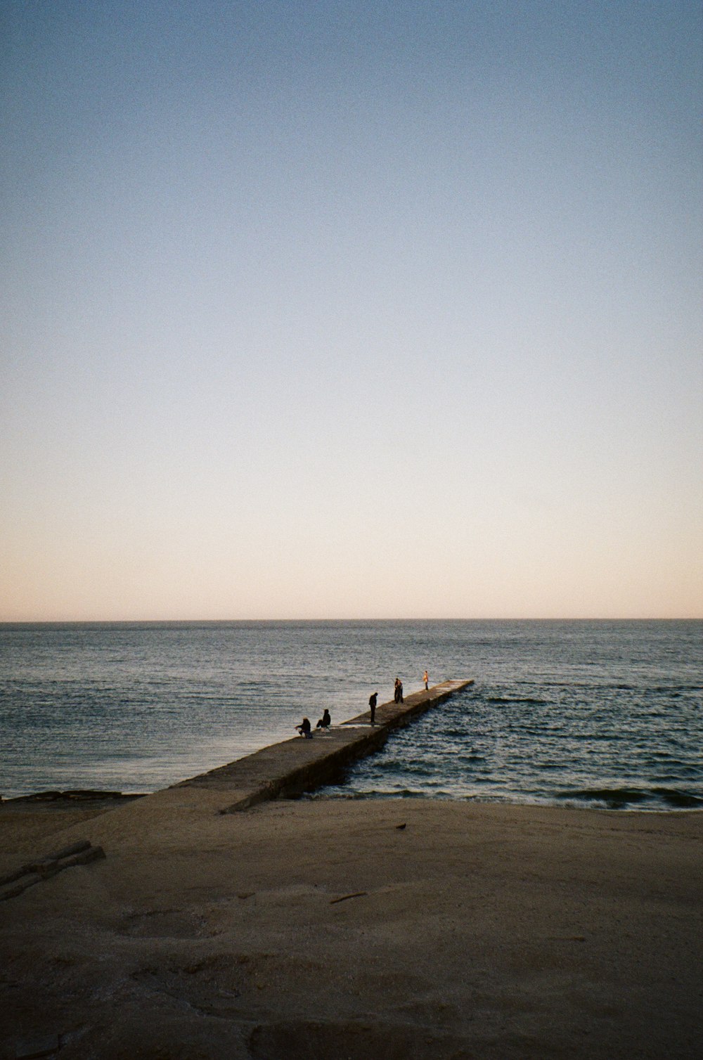 a group of people sitting on a pier next to the ocean