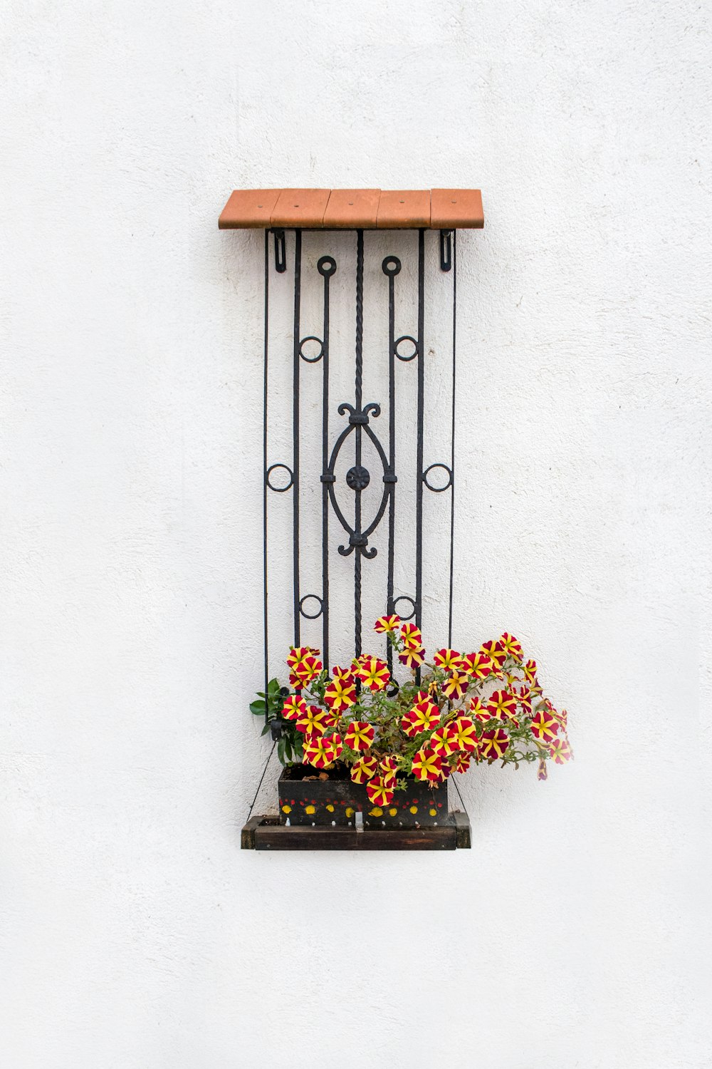a planter with flowers on a shelf on a wall