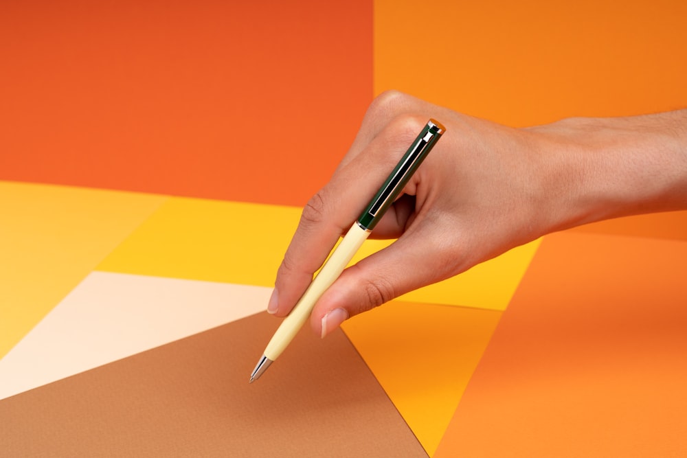 a person's hand holding a pen over a piece of paper